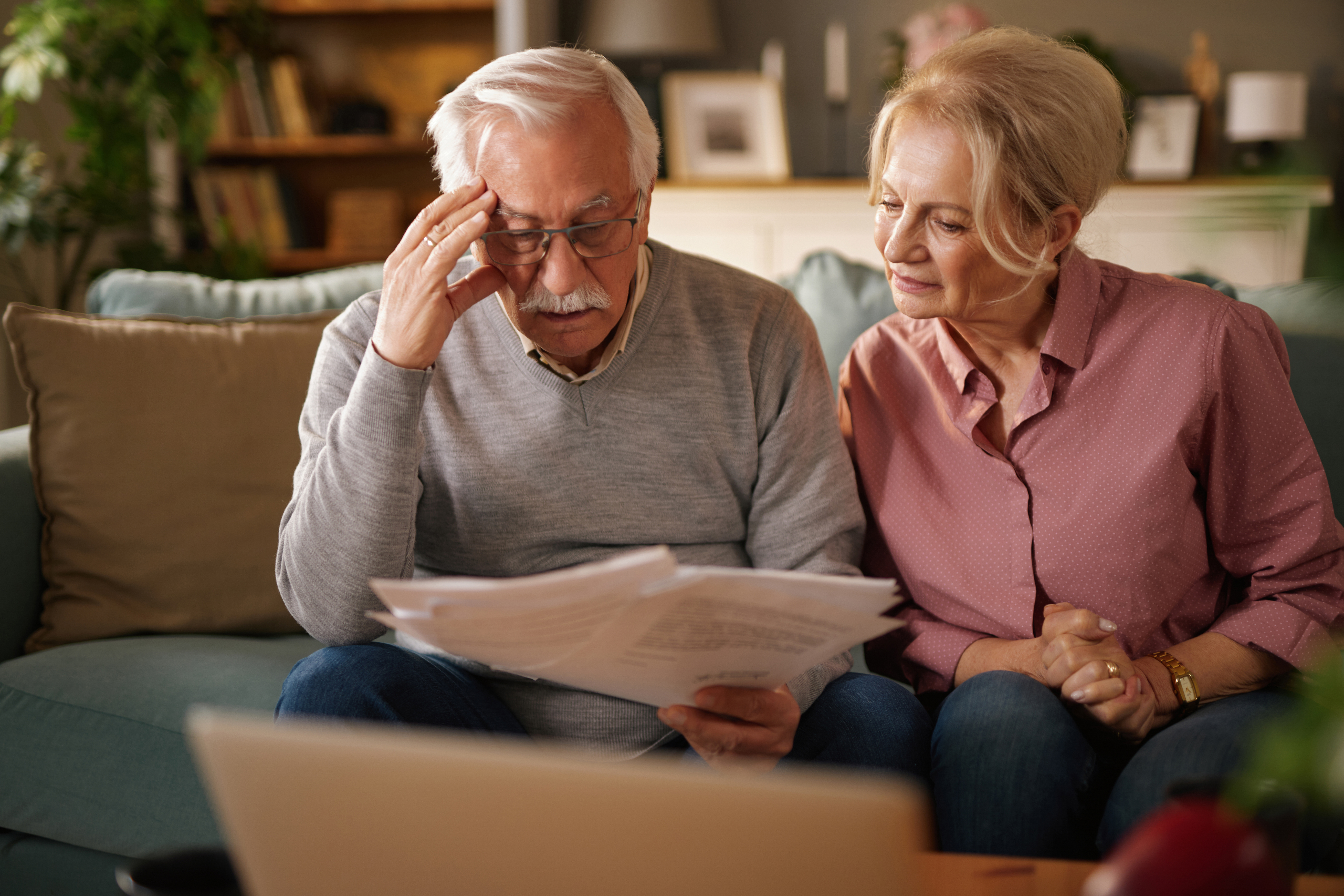 An older couple sits on a couch looking stressed. - Pension and inheritance tax reform explained. Are you prepared?